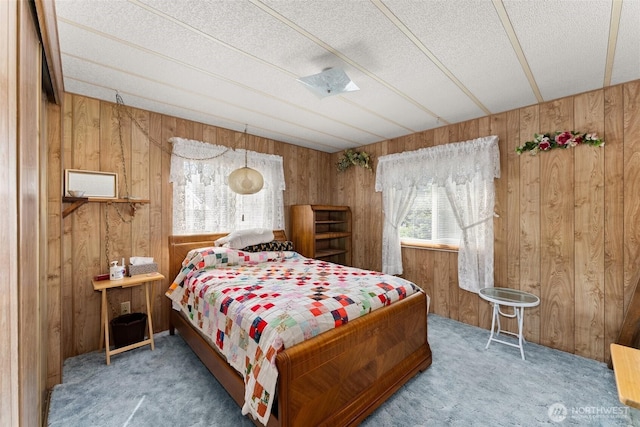 carpeted bedroom featuring wooden walls and a textured ceiling