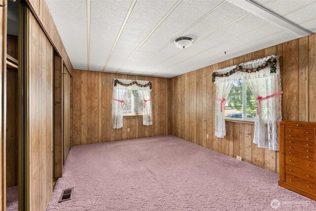 unfurnished bedroom with carpet flooring, wood walls, and a textured ceiling