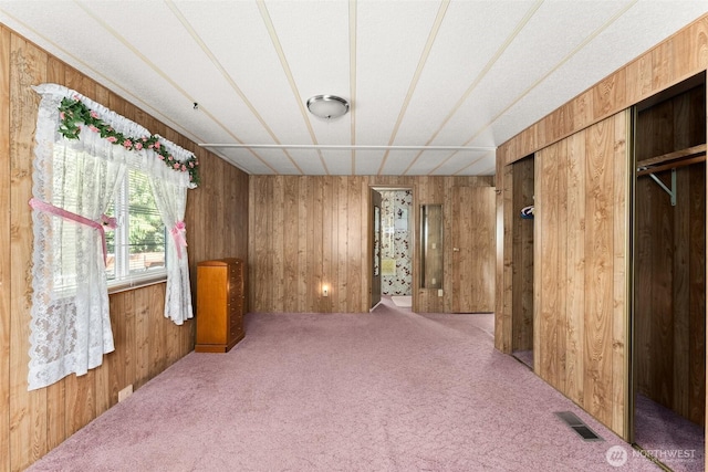 unfurnished bedroom with carpet flooring and wood walls