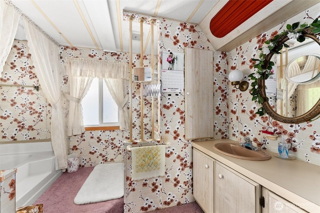 bathroom featuring wallpapered walls, vanity, a bath, and vaulted ceiling