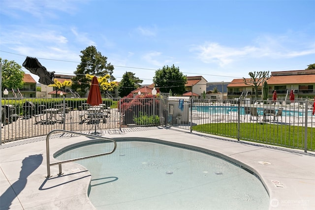 community pool with fence and a patio area
