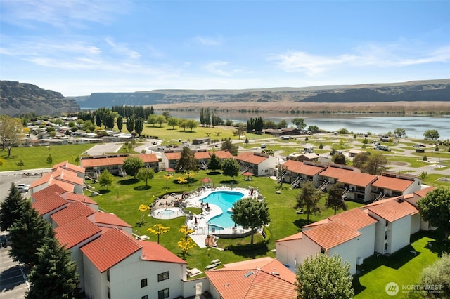 drone / aerial view of a water and mountain view and a pool