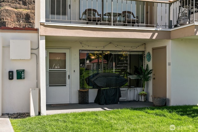 entrance to property featuring a balcony, stucco siding, and a garage