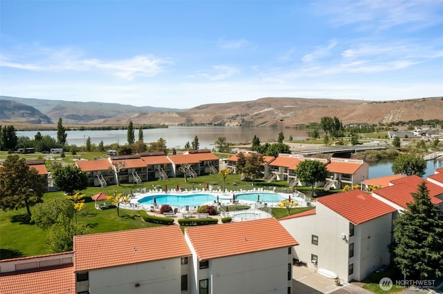 drone / aerial view of a water and mountain view and a pool