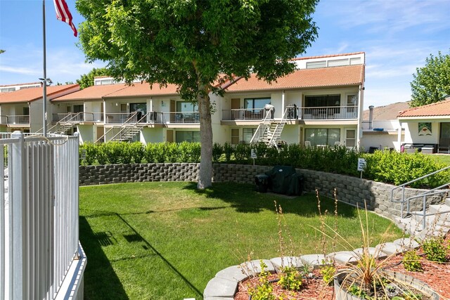 rear view of house with a tile roof, a lawn, and stucco siding
