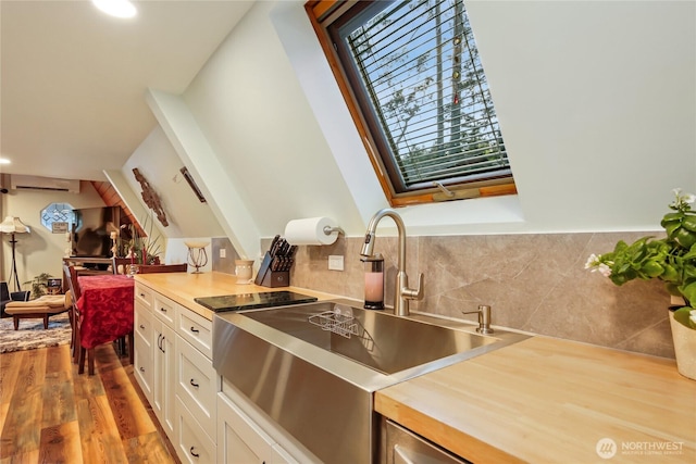 kitchen with white cabinetry, a sink, recessed lighting, wood finished floors, and tasteful backsplash