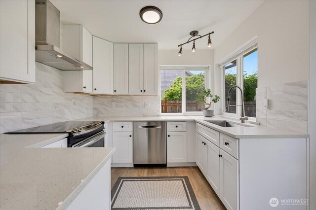 16886 Wales St SE, Monroe, WA 98272 - kitchen with wall chimney exhaust hood, appliances with stainless steel finishes, a sink, light wood-style flooring, and white cabinetry