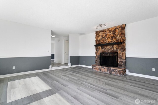 15221 42nd Ave E, Tacoma, WA 98446 - unfurnished living room featuring wood finished floors, a fireplace, baseboards, and rail lighting