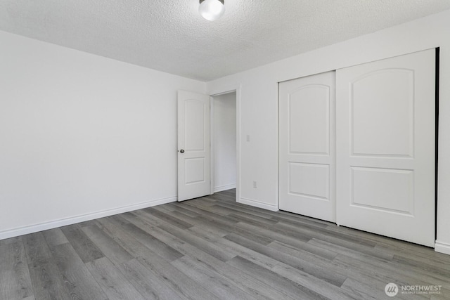 15221 42nd Ave E, Tacoma, WA 98446 - unfurnished bedroom featuring wood finished floors, a textured ceiling, a closet, and baseboards