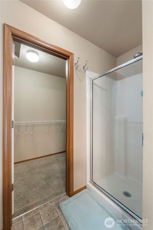20402 98th Avenue Ct E, Graham, WA 98338 - bathroom with a stall shower, a walk in closet, baseboards, and stone finish flooring