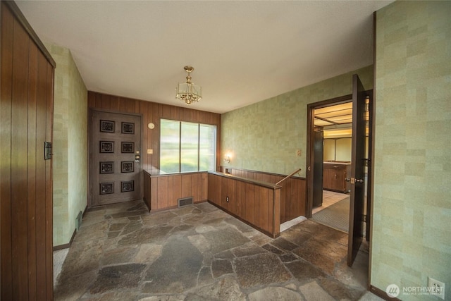 906 E 3rd Ave, Ellensburg, WA 98926 - kitchen with stone floors, brown cabinets, a chandelier, baseboards, and wainscoting