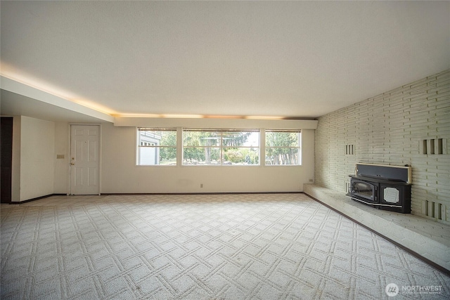 906 E 3rd Ave, Ellensburg, WA 98926 - unfurnished living room featuring a wood stove, carpet flooring, plenty of natural light, and baseboards