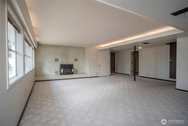 906 E 3rd Ave, Ellensburg, WA 98926 - unfurnished living room with a wood stove, baseboards, and light carpet
