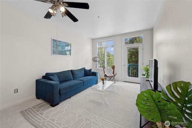living area featuring carpet, baseboards, and a ceiling fan
