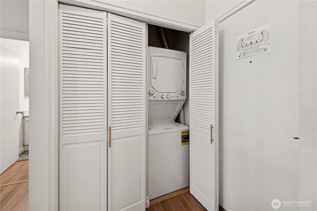 laundry room with stacked washing machine and dryer and light wood-type flooring
