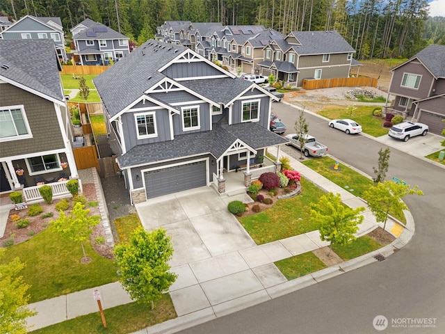 view of front of property with board and batten siding, covered porch, concrete driveway, a residential view, and an attached garage