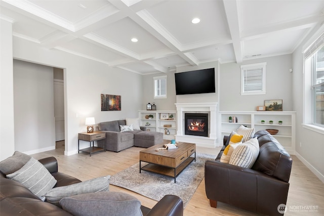 living room with beamed ceiling, light wood-type flooring, coffered ceiling, baseboards, and a glass covered fireplace