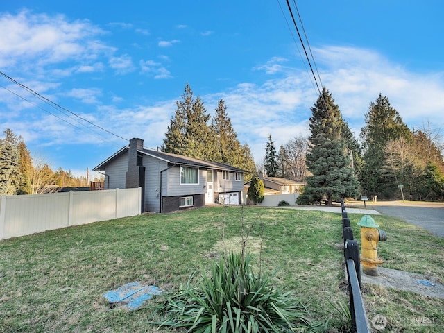 view of home's exterior with a chimney, fence, and a lawn