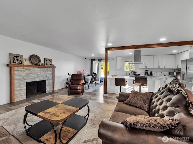 living room featuring a stone fireplace, light wood-style floors, and recessed lighting