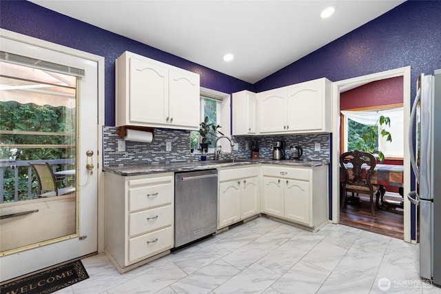 kitchen with stainless steel appliances, lofted ceiling, light marble finish floors, a sink, and tasteful backsplash