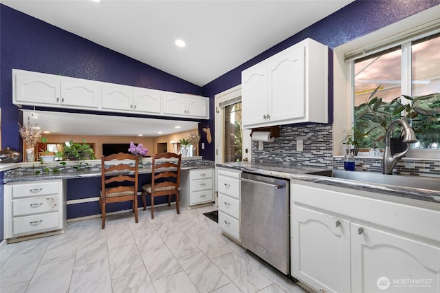 kitchen with dishwasher, vaulted ceiling, a sink, white cabinetry, and decorative backsplash