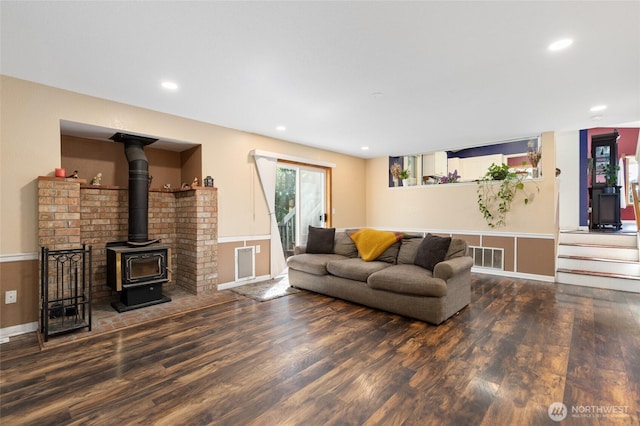living area with wood finished floors, a wood stove, and recessed lighting