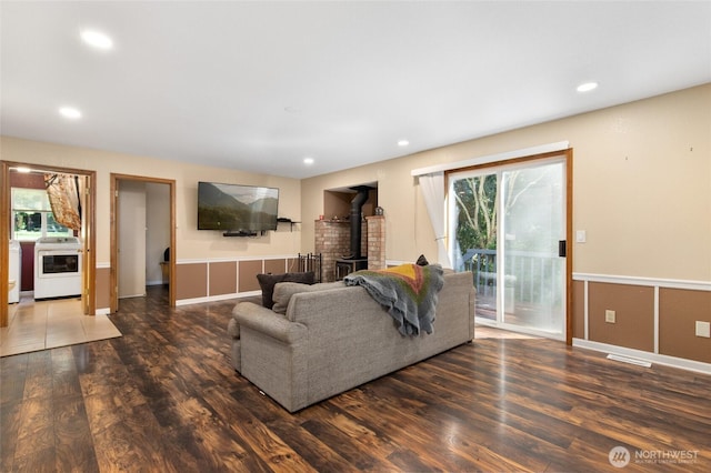 living room with a wood stove, washer / clothes dryer, wood finished floors, wainscoting, and recessed lighting