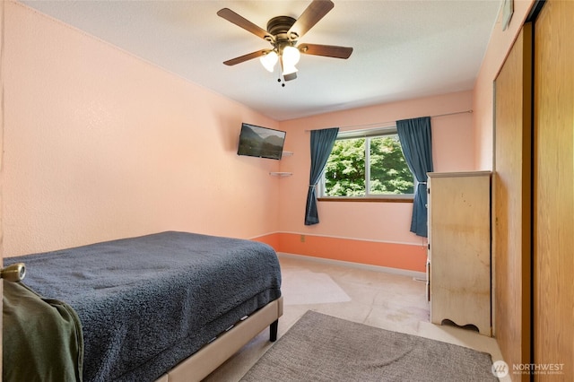 bedroom with ceiling fan, baseboards, light carpet, and a closet