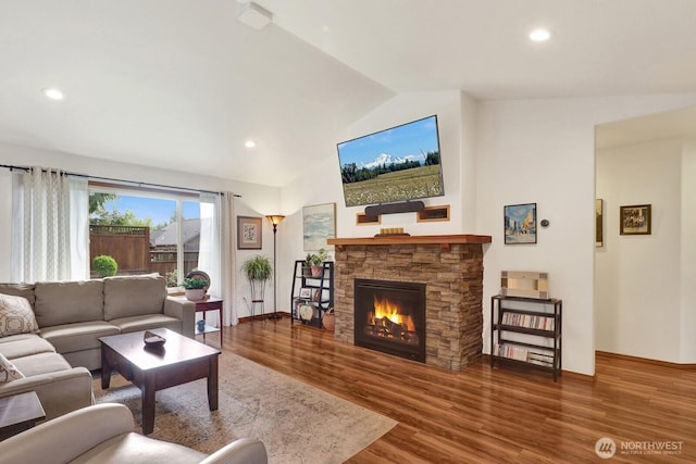 living area featuring baseboards, wood finished floors, lofted ceiling, and a fireplace