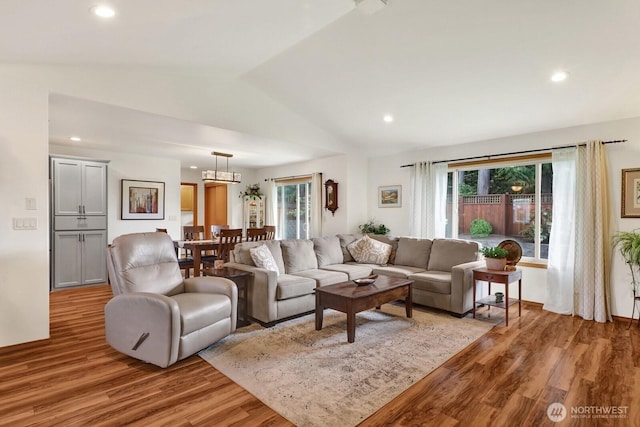 living area featuring vaulted ceiling, light wood-style flooring, and a wealth of natural light