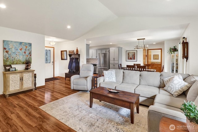 living room featuring recessed lighting, vaulted ceiling, light wood finished floors, an inviting chandelier, and baseboards