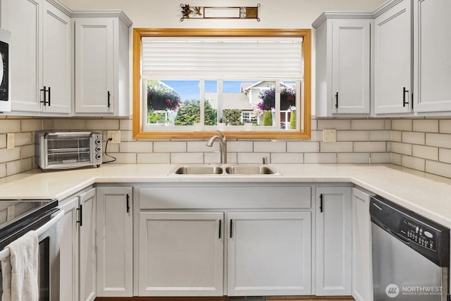 kitchen with decorative backsplash, stainless steel appliances, a toaster, and a sink