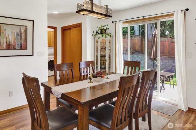 dining area featuring baseboards, washer / dryer, and light wood-style floors