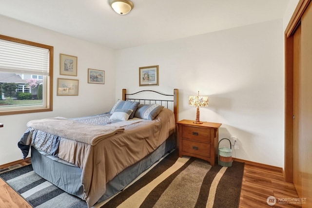 bedroom with a closet, wood finished floors, and baseboards