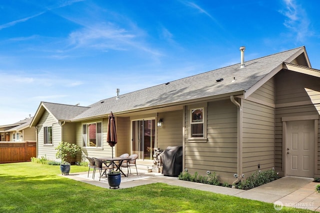 rear view of property featuring a lawn, a patio, a shingled roof, and fence
