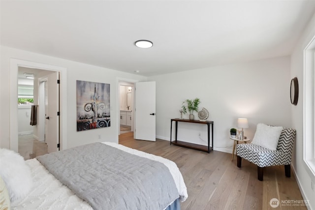bedroom with light wood-type flooring, connected bathroom, and baseboards
