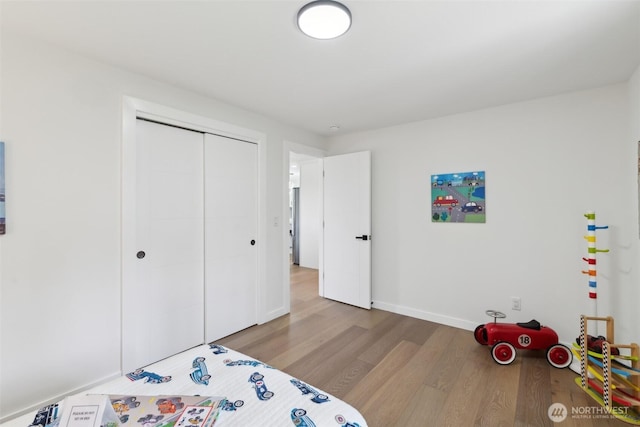 bedroom with wood finished floors, a closet, and baseboards