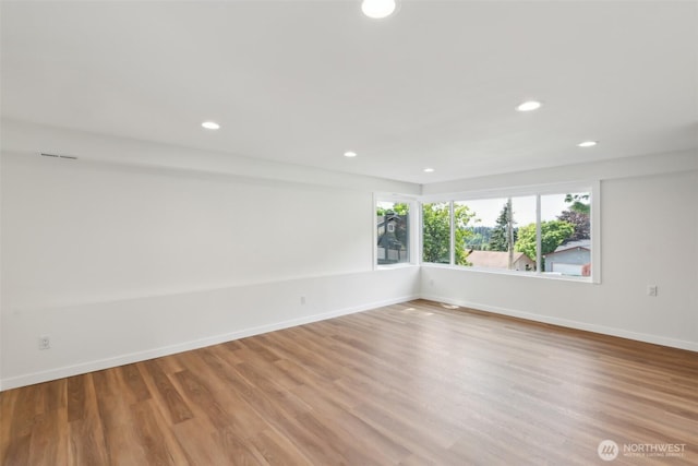 empty room with wood finished floors, recessed lighting, and baseboards