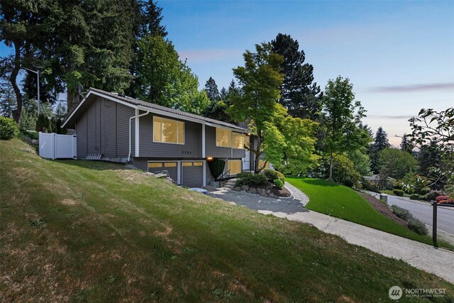 bi-level home with a garage, a front yard, and view of wooded area