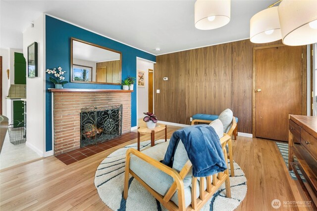 living room with wood finished floors, a brick fireplace, and baseboards