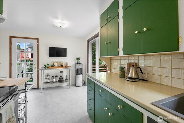 kitchen with backsplash, light countertops, green cabinetry, and black / electric stove