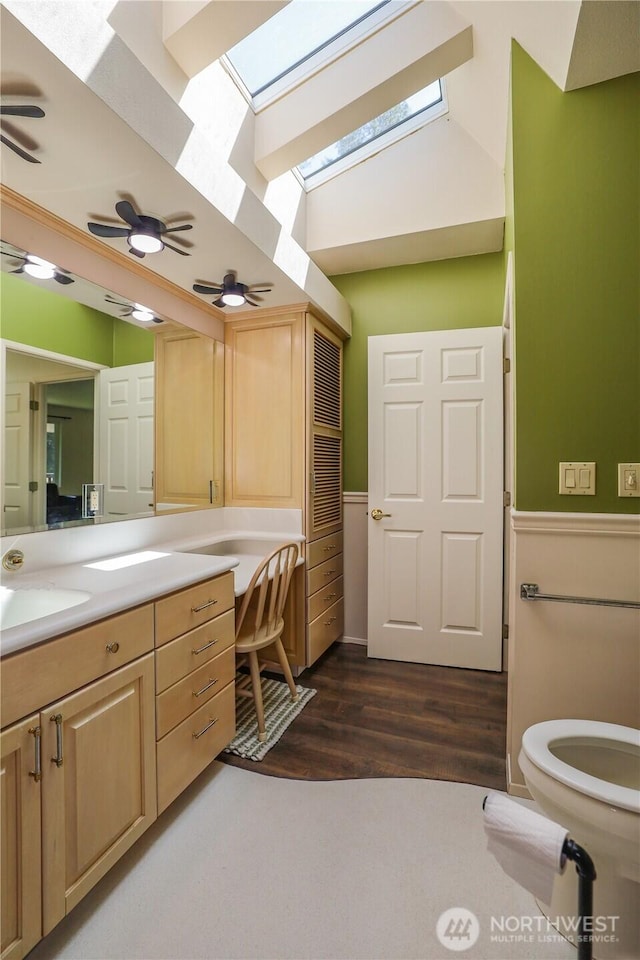 1234 Friedlander Dr, Aberdeen, WA 98520 - bathroom with a skylight, vanity, toilet, a wainscoted wall, and wood finished floors