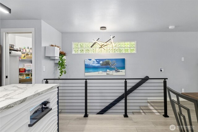 interior space with a chandelier, light wood-style flooring, and an upstairs landing