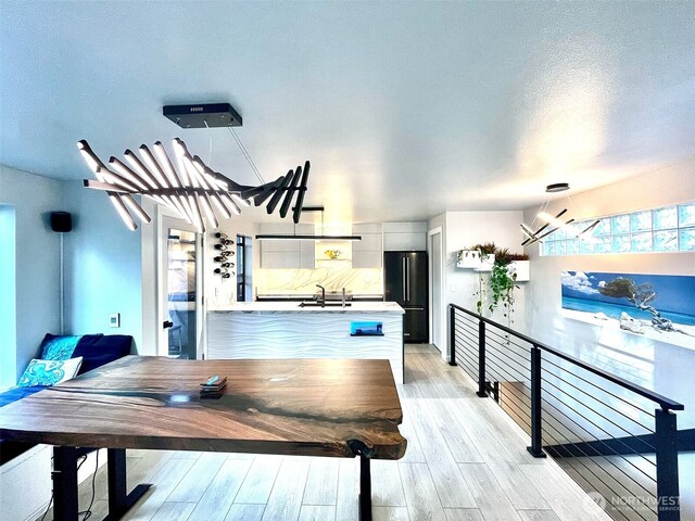 dining room featuring light wood-type flooring, a chandelier, and a textured ceiling