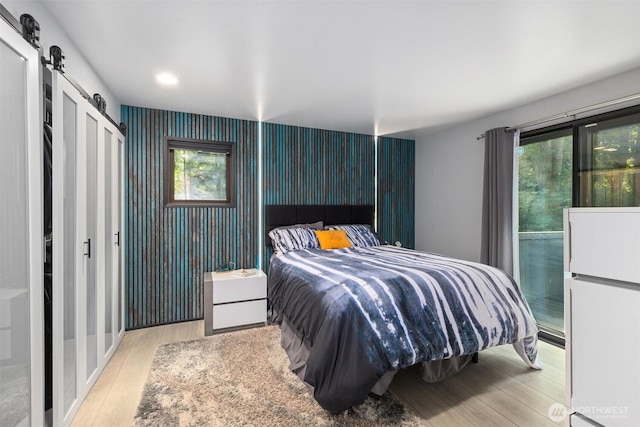 1495 Mukilteo Speedway, Mukilteo, WA 98275 - bedroom featuring a barn door, freestanding refrigerator, wood finished floors, and recessed lighting