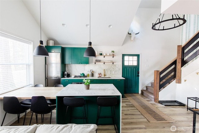 kitchen featuring green cabinetry, light wood-style floors, backsplash, open shelves, and decorative light fixtures