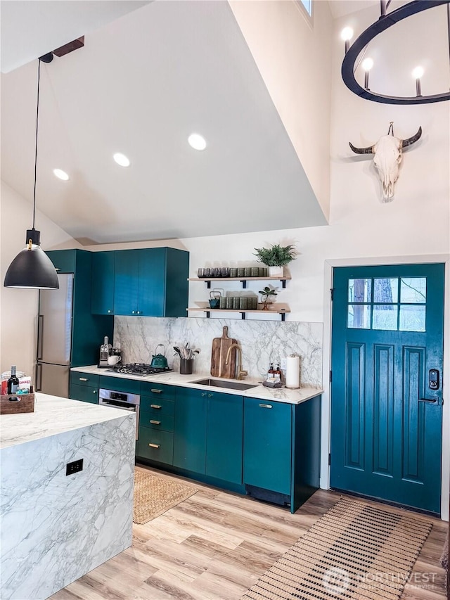 kitchen featuring a sink, appliances with stainless steel finishes, open shelves, backsplash, and light wood-style floors