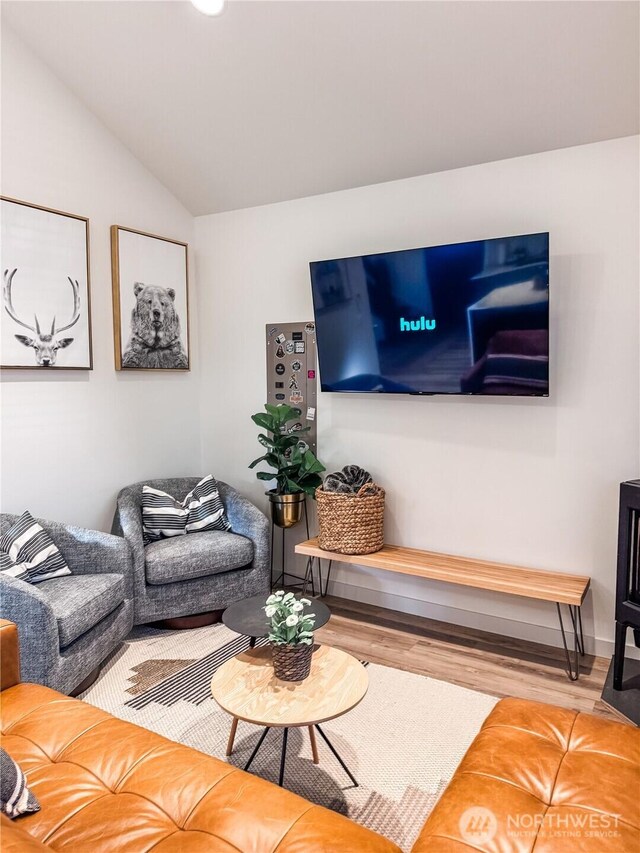 living room with wood finished floors, vaulted ceiling, and baseboards