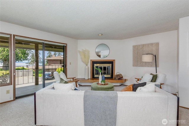carpeted living area featuring a textured ceiling and a glass covered fireplace