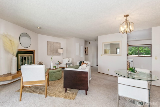 living room featuring light carpet, a textured ceiling, a chandelier, and baseboards